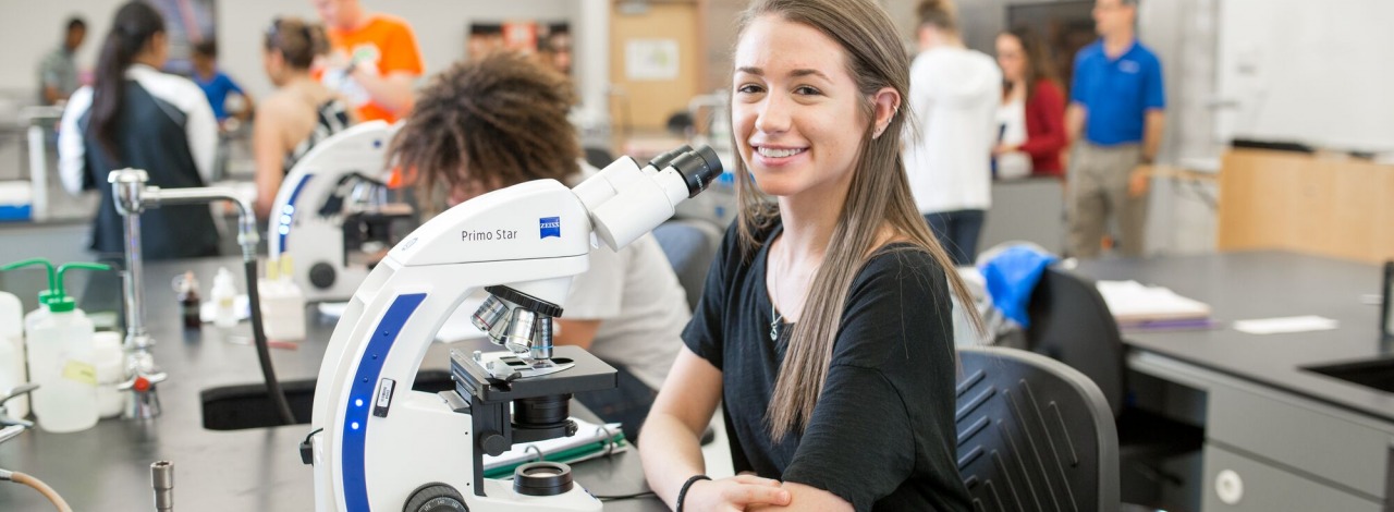Young female student smiling, sitting in a science lab