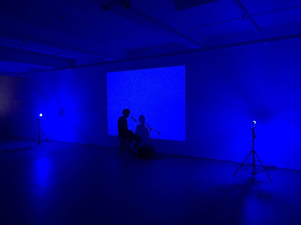 Silhouette of person sitting in front of wall with microphone