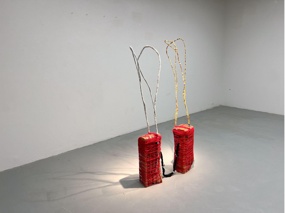 Two red art pieces on the floor of an empty room. 