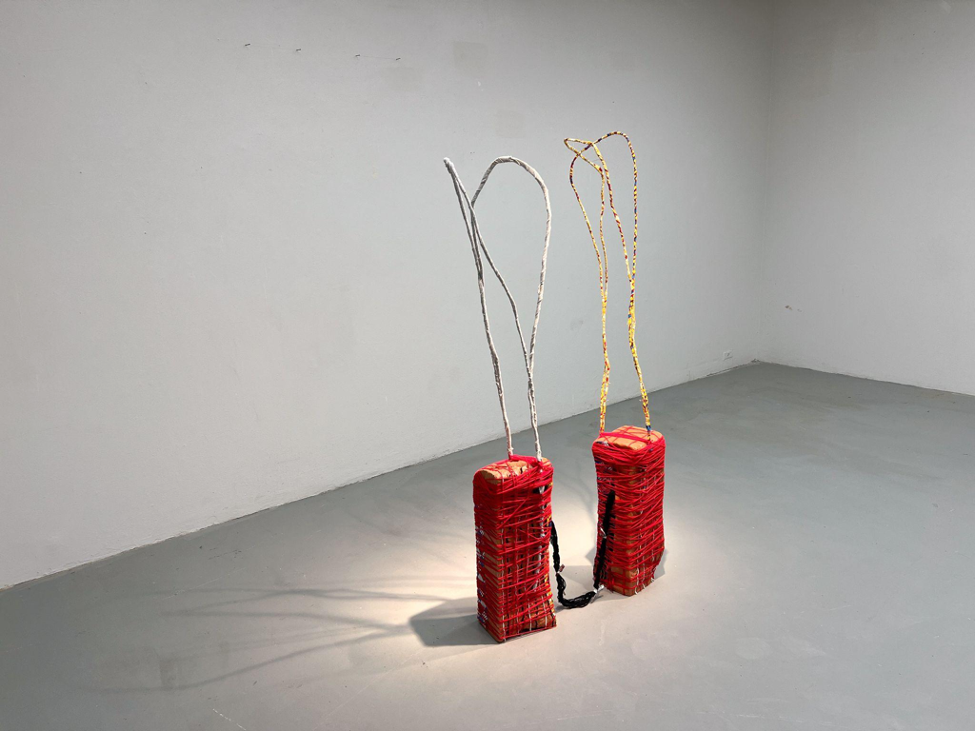 Two red art pieces on the floor of an empty room.