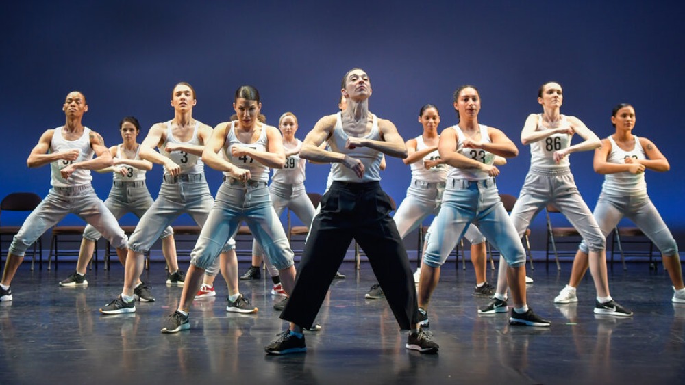 A group of dancers, each with crossed fists in front of their chest