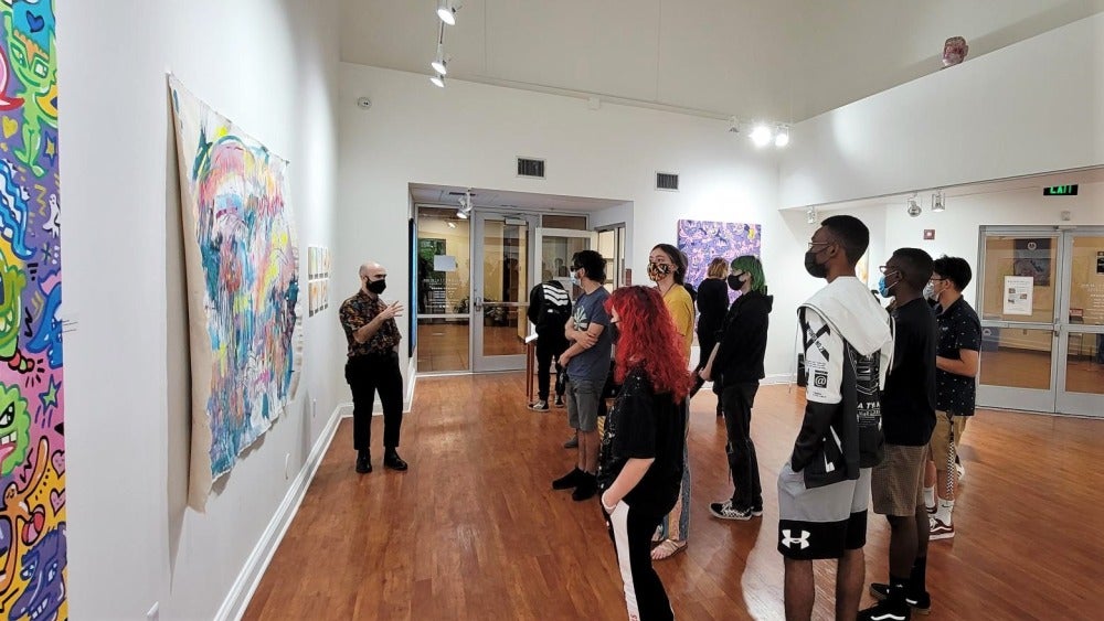 Group of students looking at painting with instructor