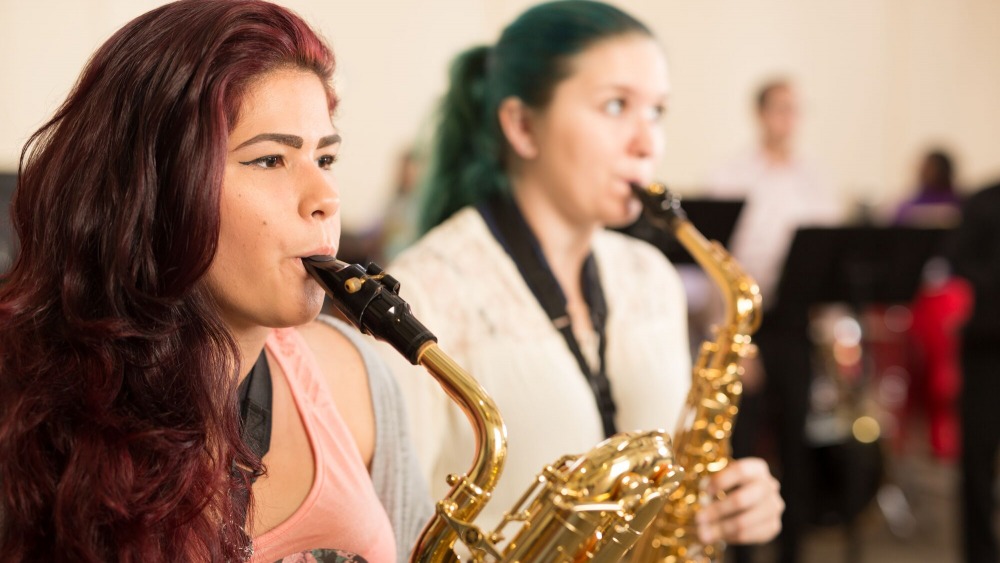 Two female band students playing a saxophone