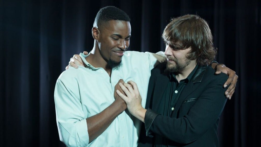 Two student-actors in friendly embrace