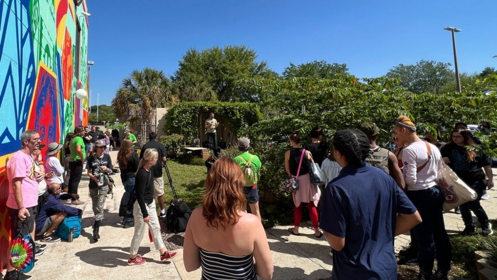 Group watching a performance in front of a mural