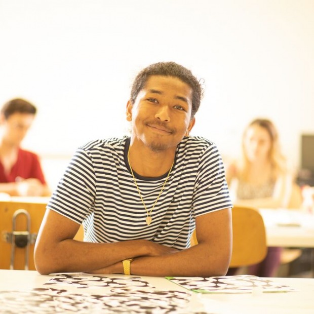 Student smiling at a desk in their classroom. 
