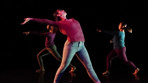 Dancer in jeans and red shirt with arms and head thrown back