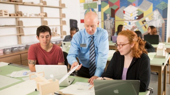 Student examining architectural model with instructor
