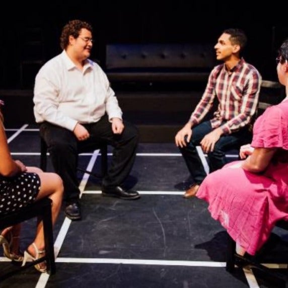 Four people sitting in chairs facing one another