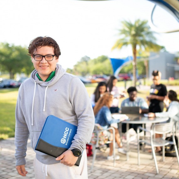 student with HCC notebook at Brandon Campus courtyard