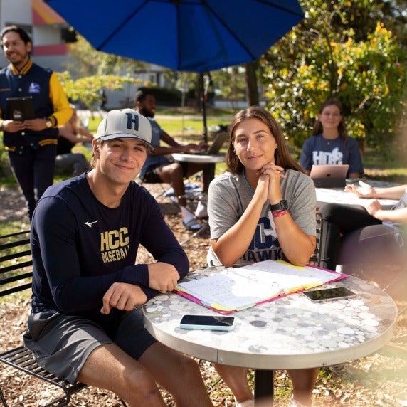 Two students sitting at table with open notebook