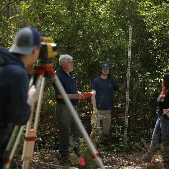 Surveyor in wooded area with three other people