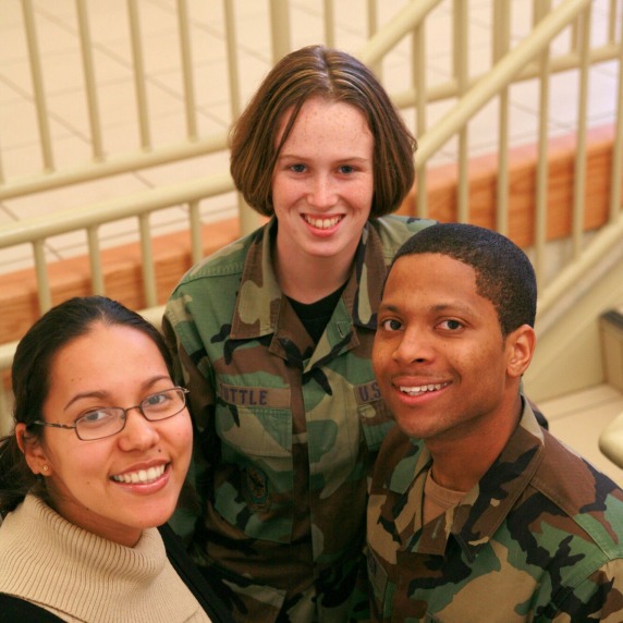 Two students in military uniform and one student in civilian attire on a staircase