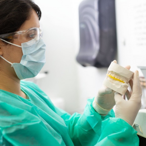 female dental hygiene student inspecting a moulding of teeth 
