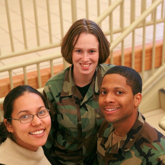 Two students in uniform and one student in civilian attire standing on a stairwell