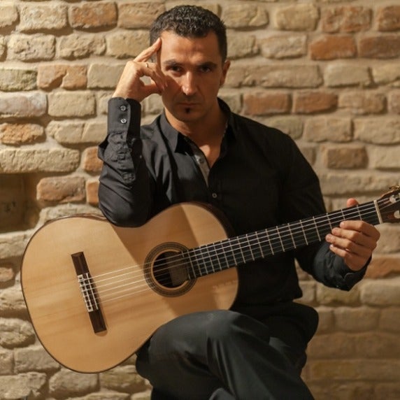 Photo of Roberto Tascini seated with guitar