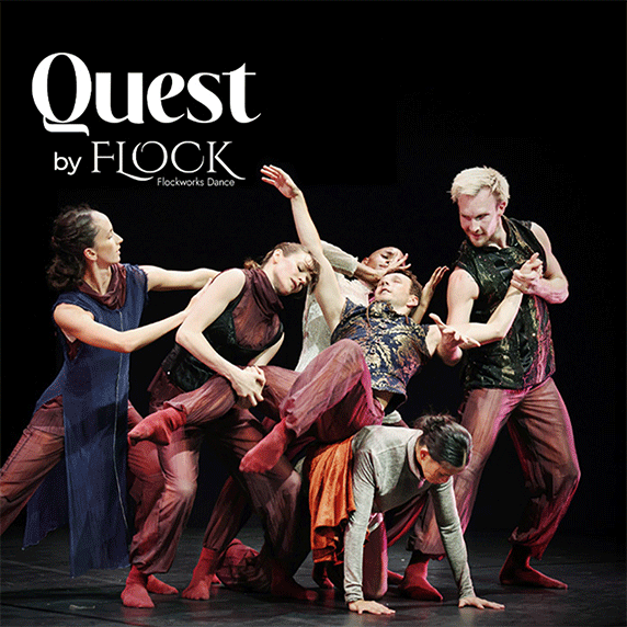 A group of dancers performing a dynamic routine on a dark stage
