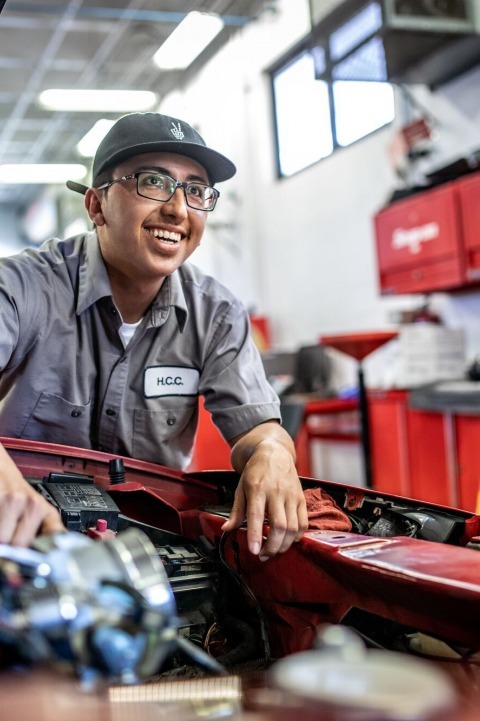 Automotive Technician student standing over engine bay