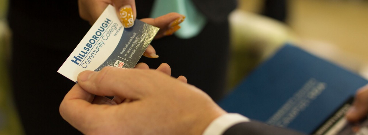 close-up of two people exchanging a business card.