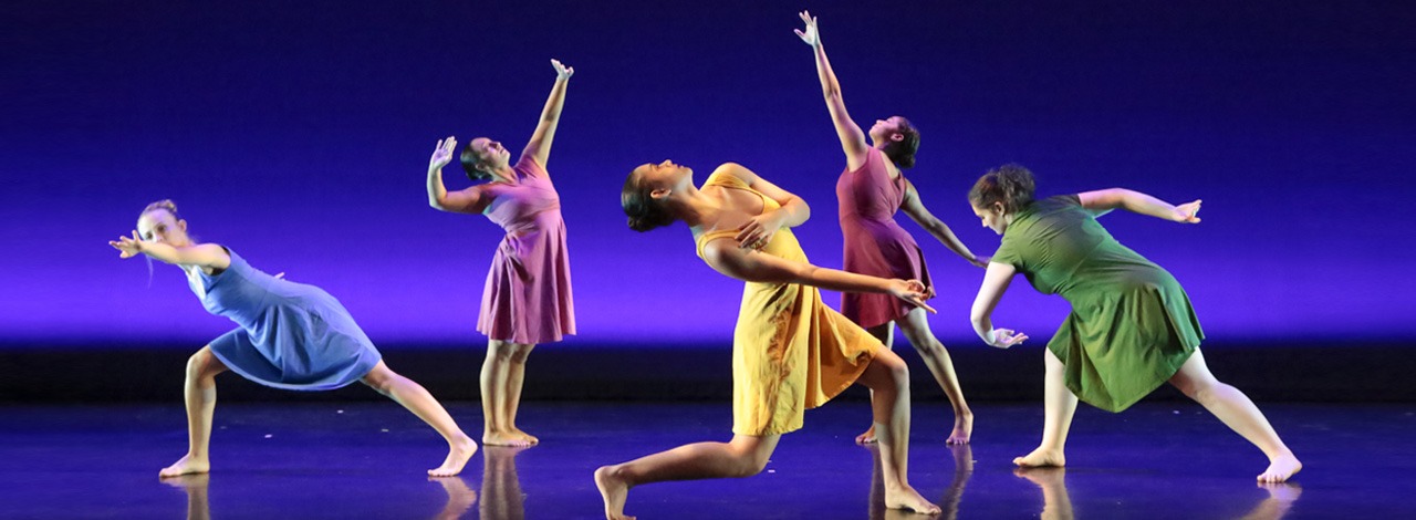 5 dancers in colorful dresses in front of a dark blue background