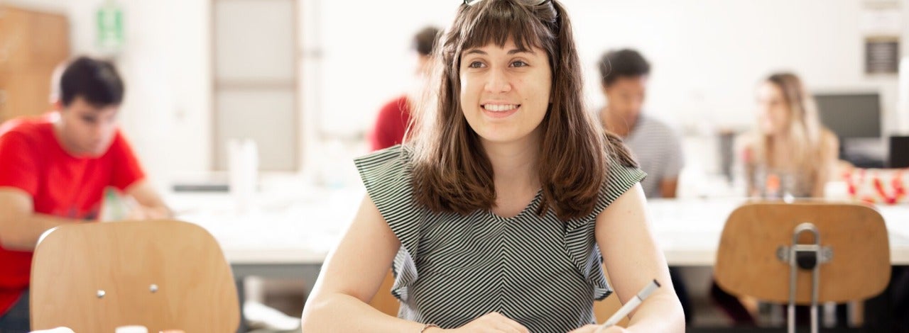 Female student smiling and drawing a tessellation in an art classroom