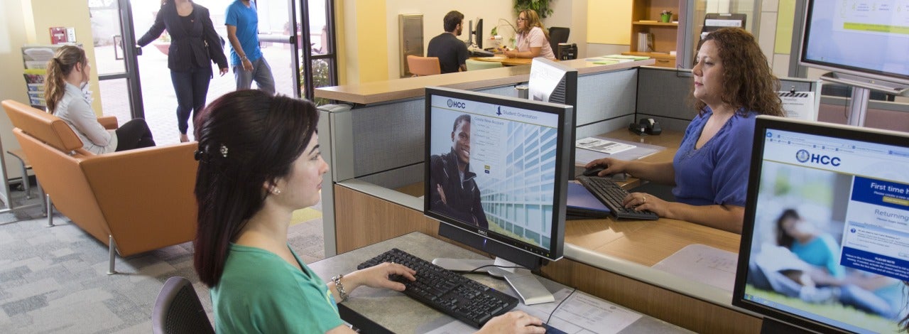 people using the computers at the Connection Center, two individuals are walking in