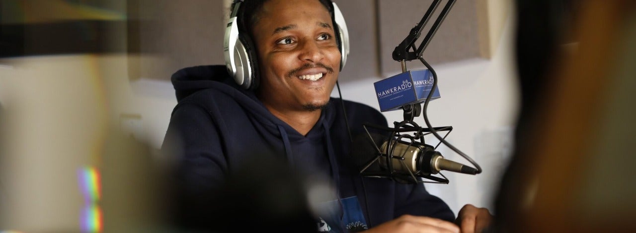 A male student sitting in the Hawk Radio station. 