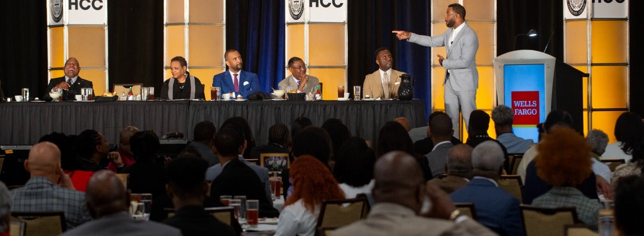 A group of people listen to actor, Omari Hardwick, deliver a keynote speech from the BBCB Summit stage. 