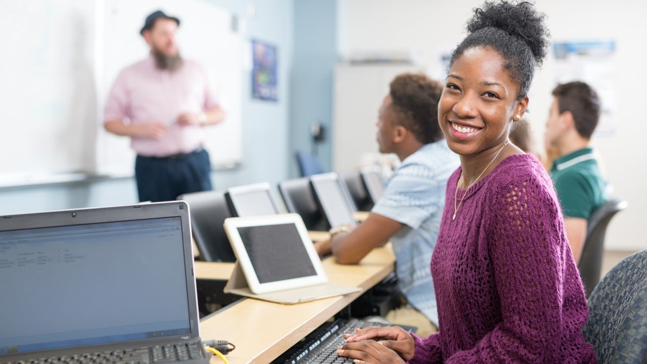 Student sitting at desk with computer sitting in front of her. 