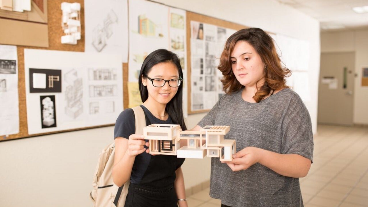 Students holding a project in classroom hallway.