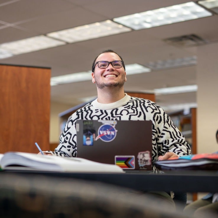 Student sitting at  a table with a laptop open. 