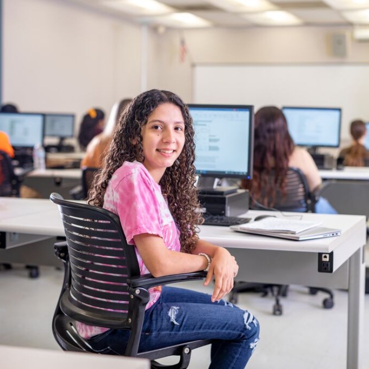 Student sitting in front of computer looking at camera