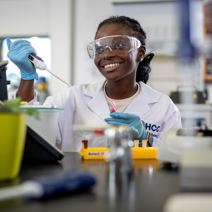 Black female student in white lab coat smiling. 