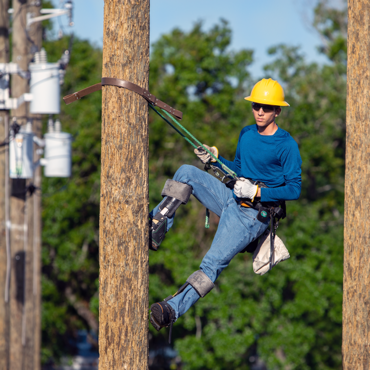 Male student strapped to a wooden pole wearing safety gear. 